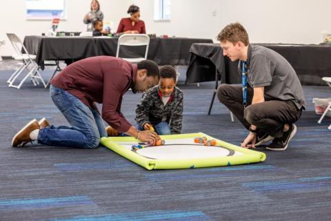 Photo of a Do Space staff and a man and a son playing with a tech kit